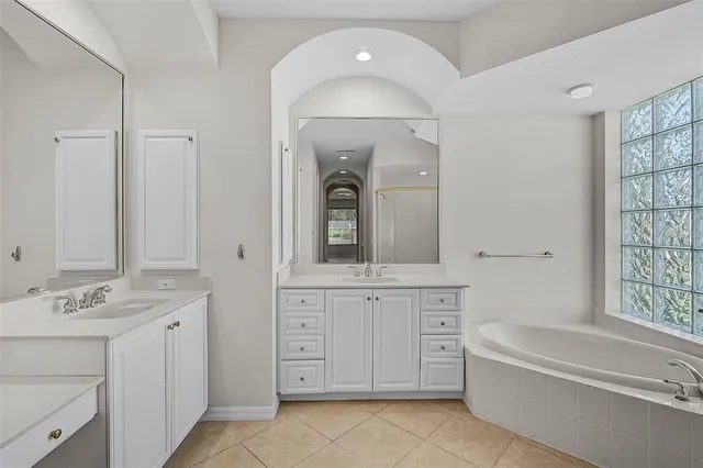 a bathroom with a granite countertop sink a bathtub a mirror a vanity and bathtub