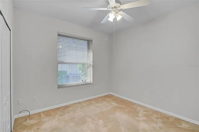 an empty room with a window and a fan