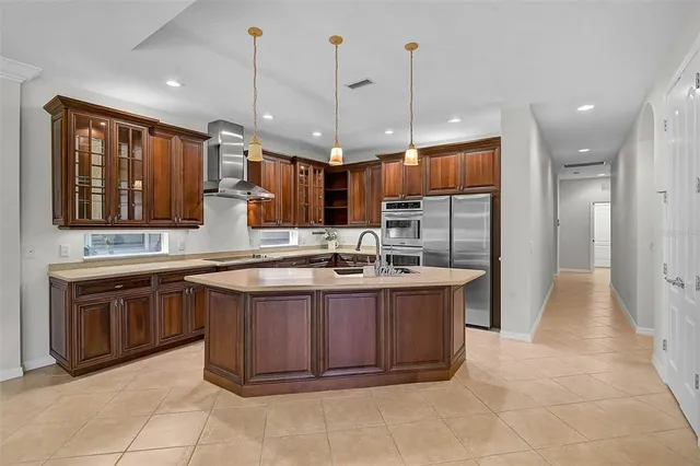 a large kitchen with kitchen island granite countertop a sink a counter top space appliances and cabinets