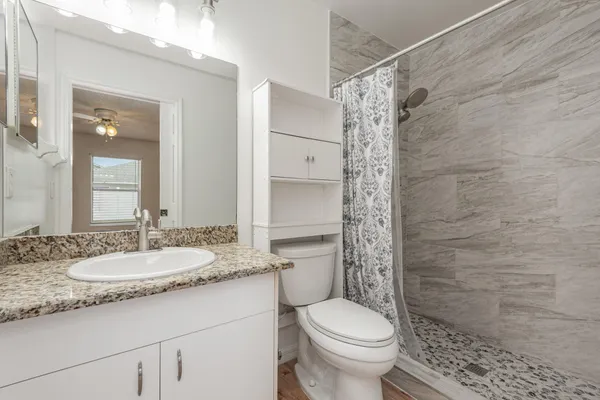 a bathroom with a granite countertop sink a toilet and shower