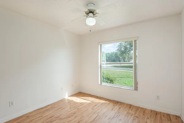 an empty room with wooden floor ceiling fan and windows