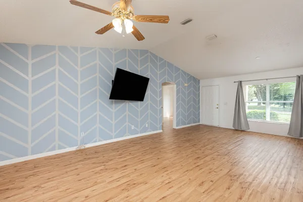 a view of empty room with wooden floor and fan