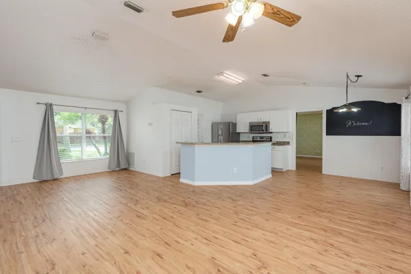 a view of a kitchen with a sink dishwasher and a refrigerator with wooden floor