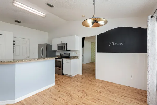 a kitchen with stainless steel appliances granite countertop a refrigerator a stove top oven a sink and dishwasher with wooden floor