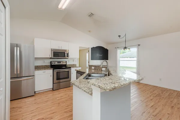 a kitchen with granite countertop a refrigerator stove and oven