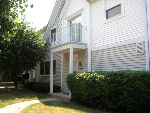 a view of a house with a small yard and large tree