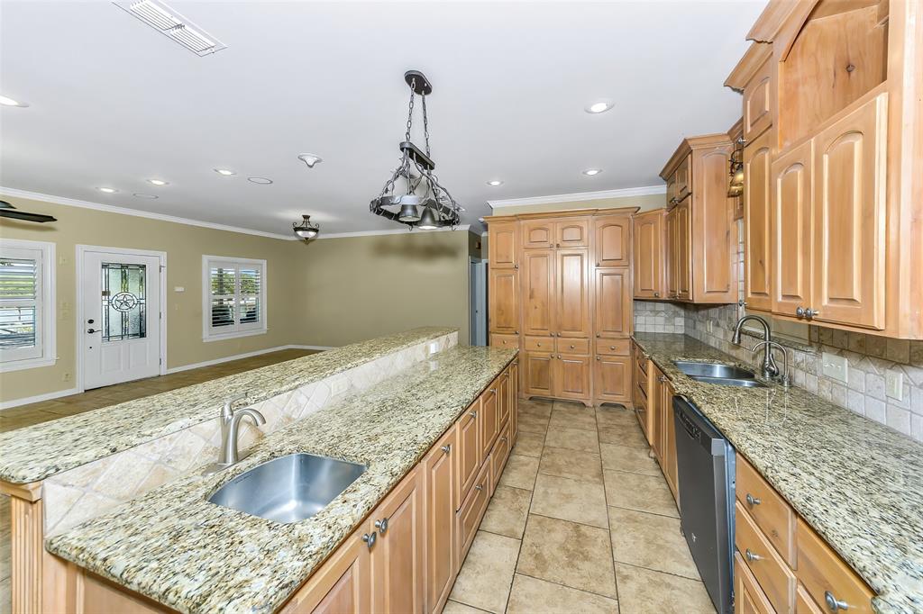 566 Selma Park Road Bowie, TX 76230 - Photo 12 of 40 Kitchen featuring granite countertops, extensive wood cabinetry, tile flooring, and a double basin sink with a brushed nickel faucet