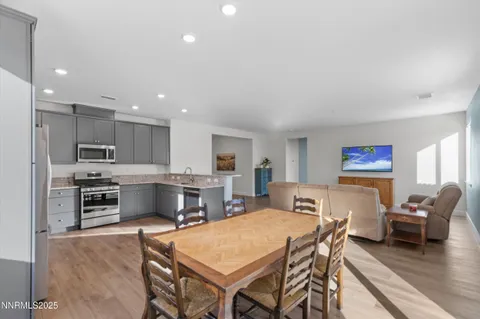 a living room with stainless steel appliances furniture a rug and a kitchen view