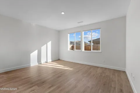 a view of an empty room with wooden floor and window