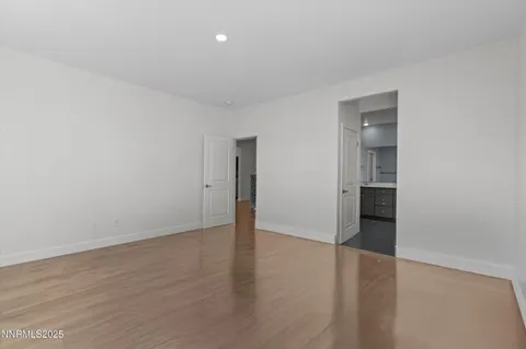 a view of an empty room with wooden floor and closet