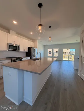 a kitchen with stainless steel appliances granite countertop a sink a stove and a wooden floors