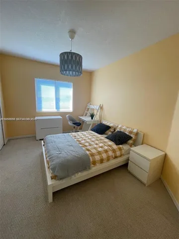 a bedroom with a bed couch chandelier and a window
