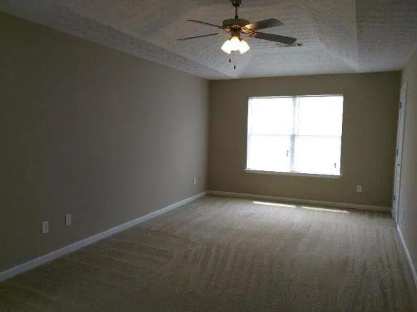 an empty room with a window and a fan