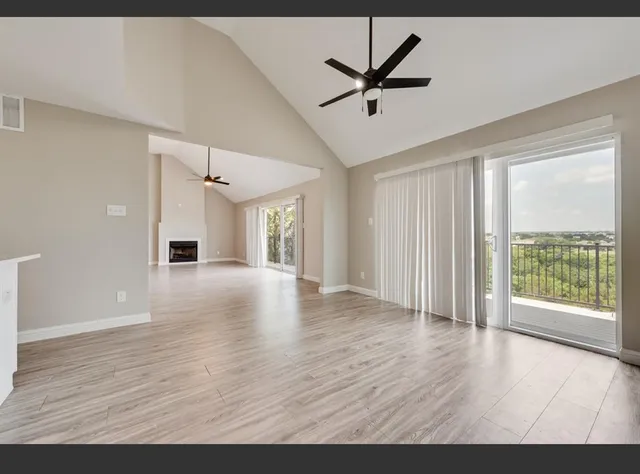 a view of an empty room with a window and wooden floor