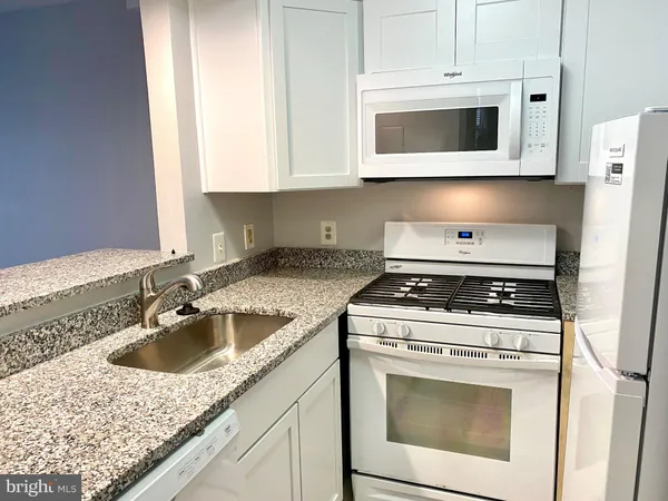 a kitchen with granite countertop a stove sink and microwave