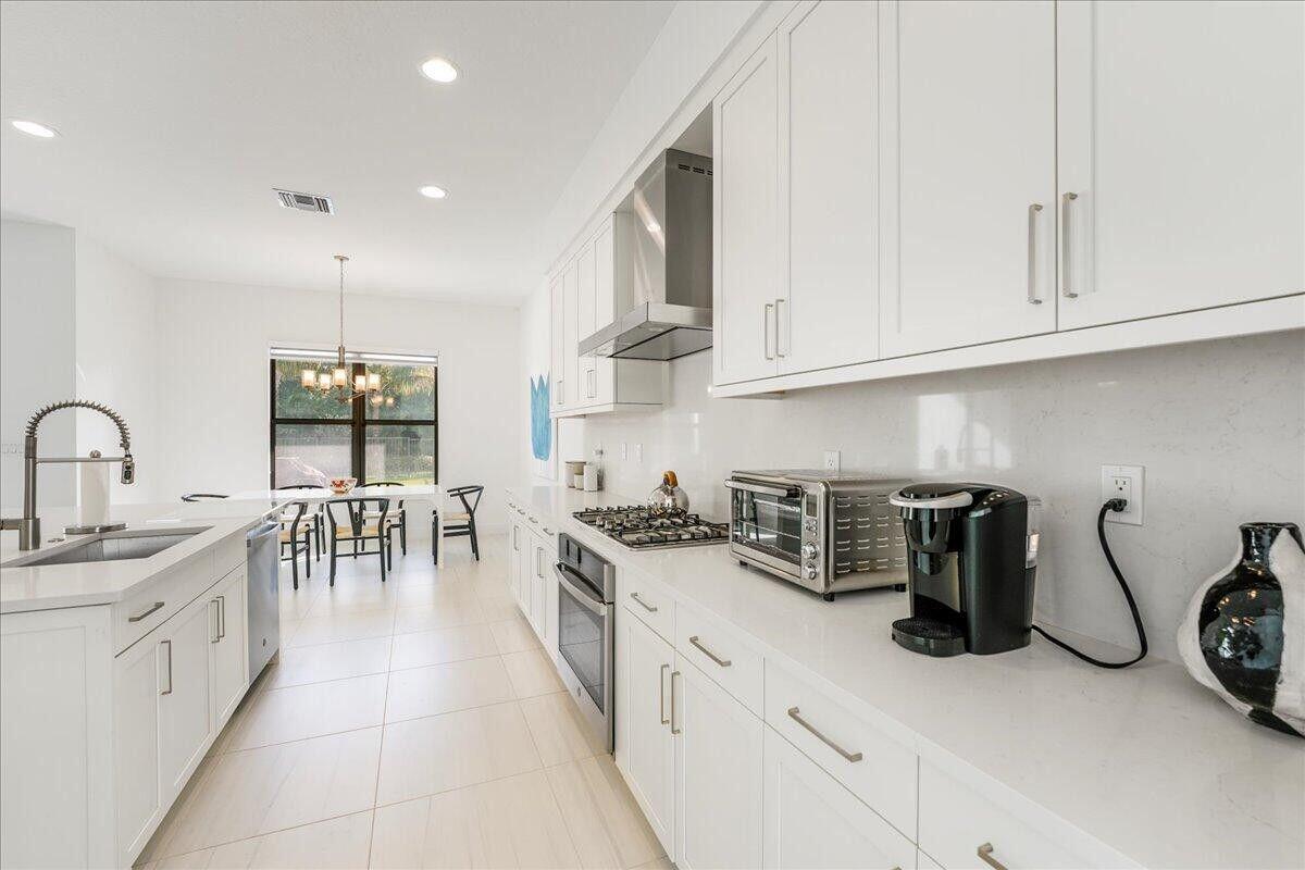 17496 Sparkling River Road Boca Raton, FL 33496 - Photo 7 of 36 a kitchen with stainless steel appliances granite countertop a sink a stove and white cabinets