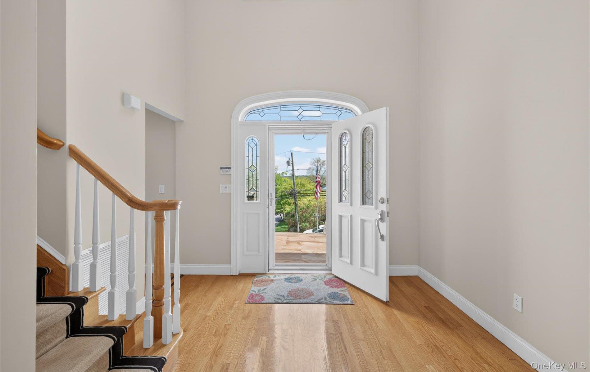 16 East Slope Road Bayville, NY 11709 - Photo 5 of 48 Foyer featuring an arched glass-paneled front door with sidelights and hardwood flooring.