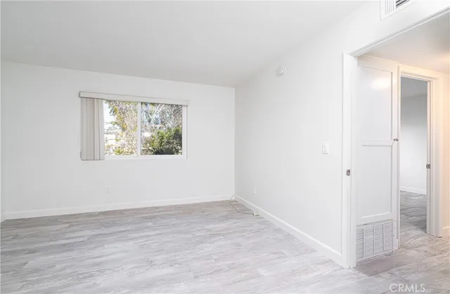 an empty room with wooden floor and window