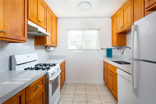 a kitchen with stainless steel appliances granite countertop a sink a stove a refrigerator cabinets and a window