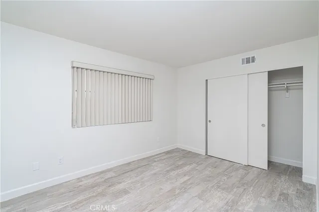 a view of an empty room with wooden floor and closet area