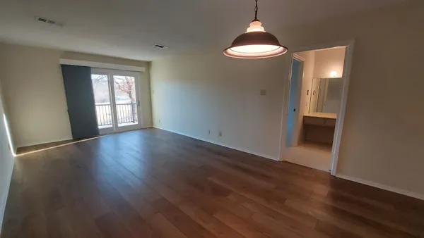 an empty room with wooden floor and windows