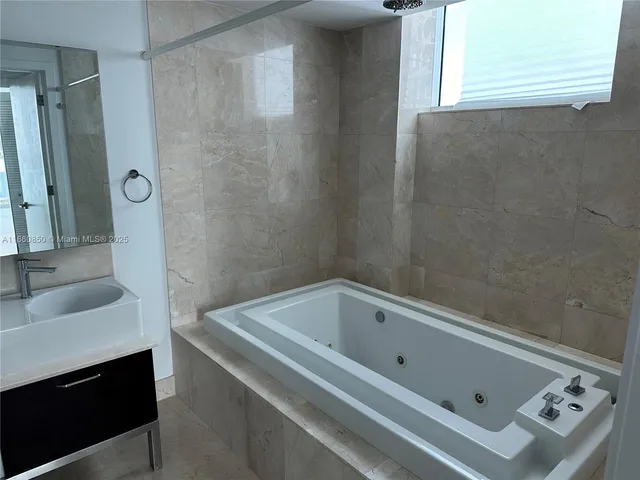 a bathroom with a tub sink and mirror
