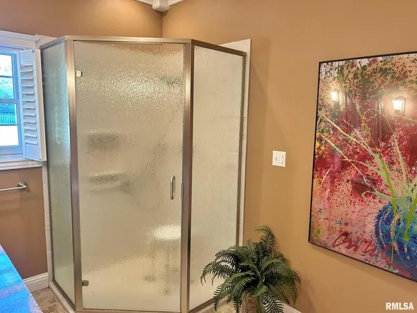 a bathroom with a glass shower door and a window