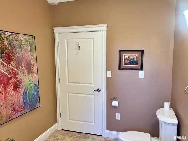 a bathroom with a toilet and a painting on the wall
