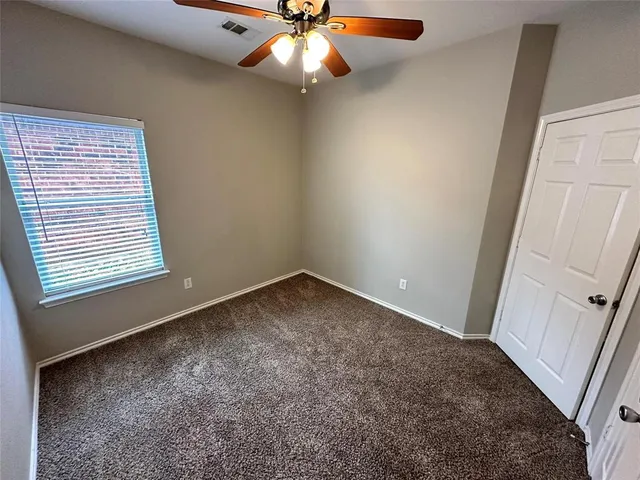 an empty room with a window and a fan