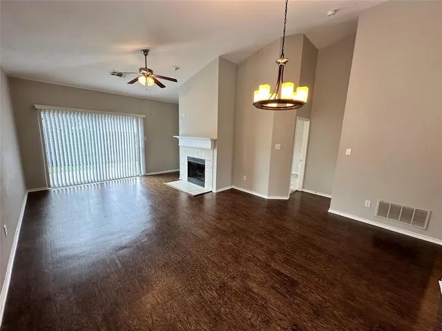 an empty room with wooden floor chandelier and windows