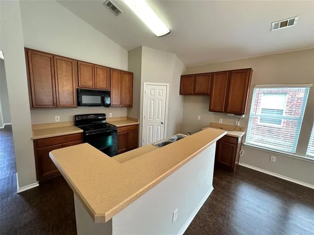 a kitchen with stainless steel appliances a sink a stove a microwave a refrigerator a sink and cabinets