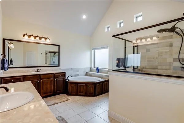 a spacious bathroom with a tub sink and mirror