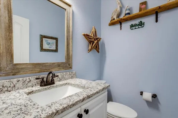 a bathroom with a granite countertop sink a toilet and mirror