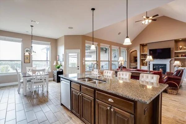 a kitchen with granite countertop a table chairs stove a sink and dishwasher with wooden floor