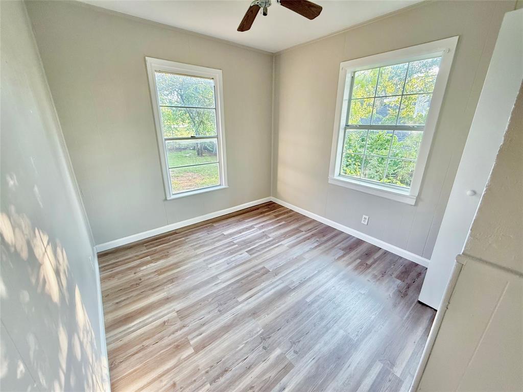 428 East Elm Street Denison, TX 75021 - Photo 11 of 18 a view of an empty room with wooden floor and a window