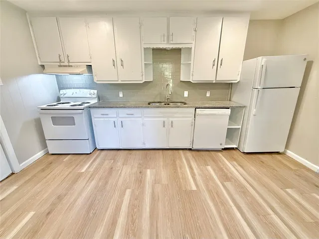a kitchen with granite countertop white cabinets and white appliances