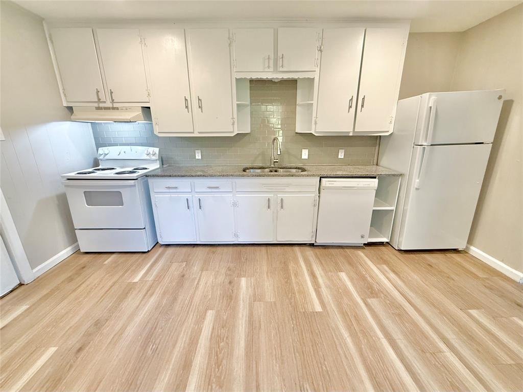 428 East Elm Street Denison, TX 75021 - Photo 5 of 18 a kitchen with granite countertop white cabinets and white appliances