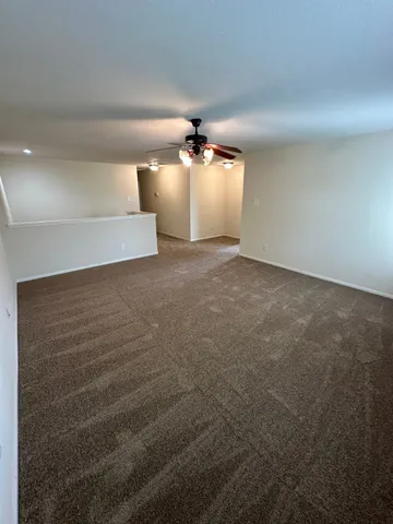 en empty room with windows and ceiling fan