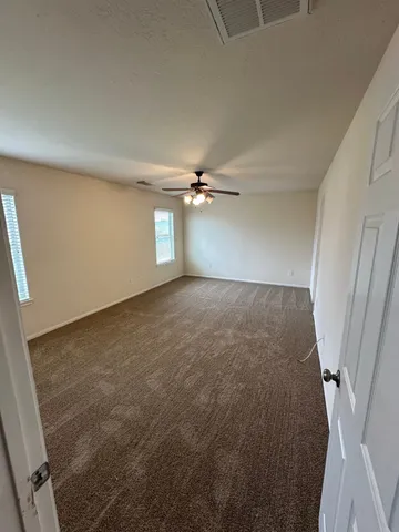 an empty room with chandelier fan and windows