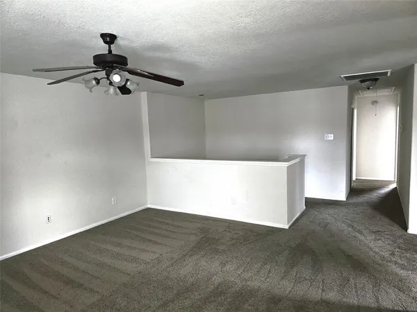 an empty room with windows and ceiling fan