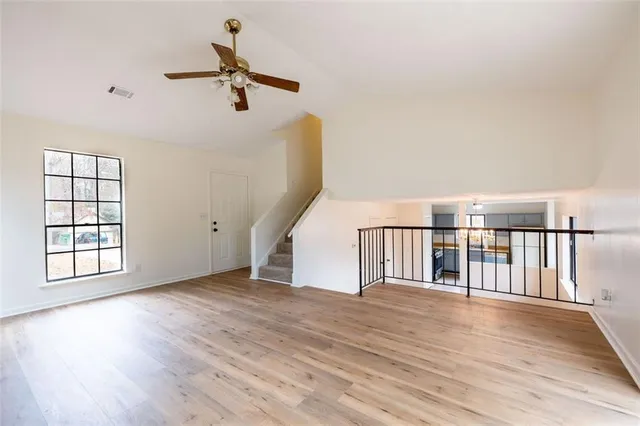 a view of empty room with wooden floor and fan