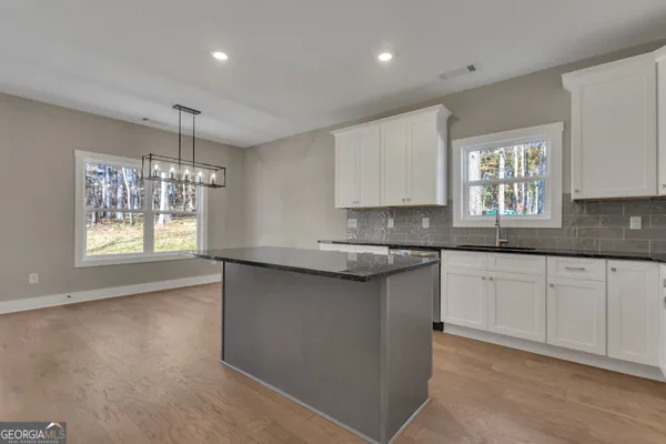 a kitchen with granite countertop a refrigerator oven a sink dishwasher and white cabinets