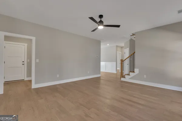 a view of an empty room with wooden floor and a window