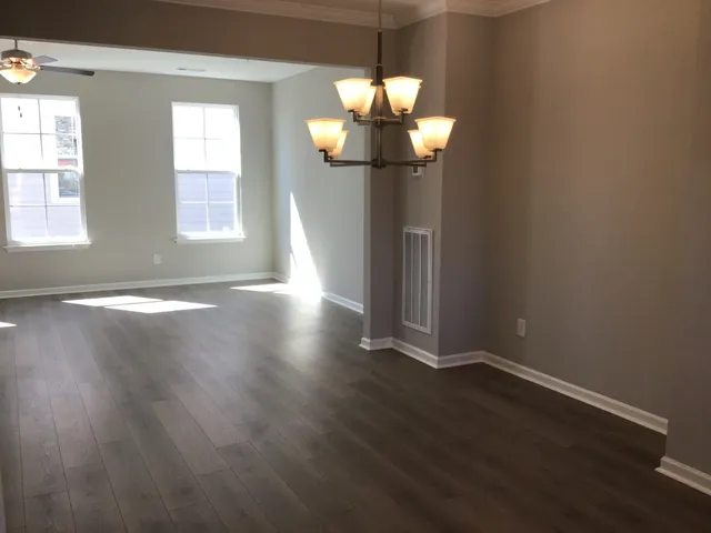 a view of a livingroom with a large window wooden floor and chandelier