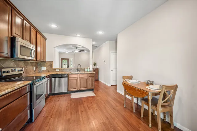 a large kitchen with stainless steel appliances granite countertop a lot of counter space and wooden floors
