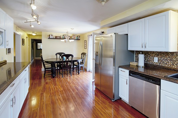 486 Cotuit Road Mashpee, MA 02649 - Photo 12 of 29 a kitchen with stainless steel appliances granite countertop a refrigerator a stove a sink a dining table and chairs with wooden floor