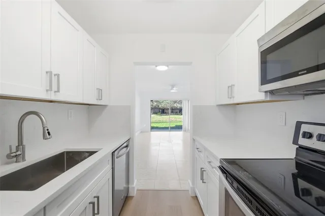 a kitchen with stainless steel appliances granite countertop a sink and a stove top oven with wooden floor