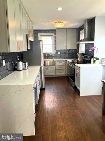 a kitchen with a sink a stove cabinets and a wooden floor