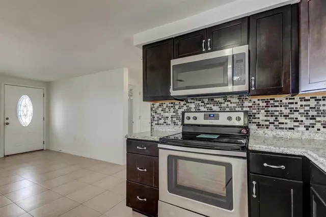 a kitchen with granite countertop a stove top oven microwave and cabinets
