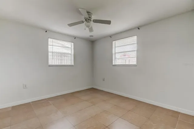an empty room with windows and fan